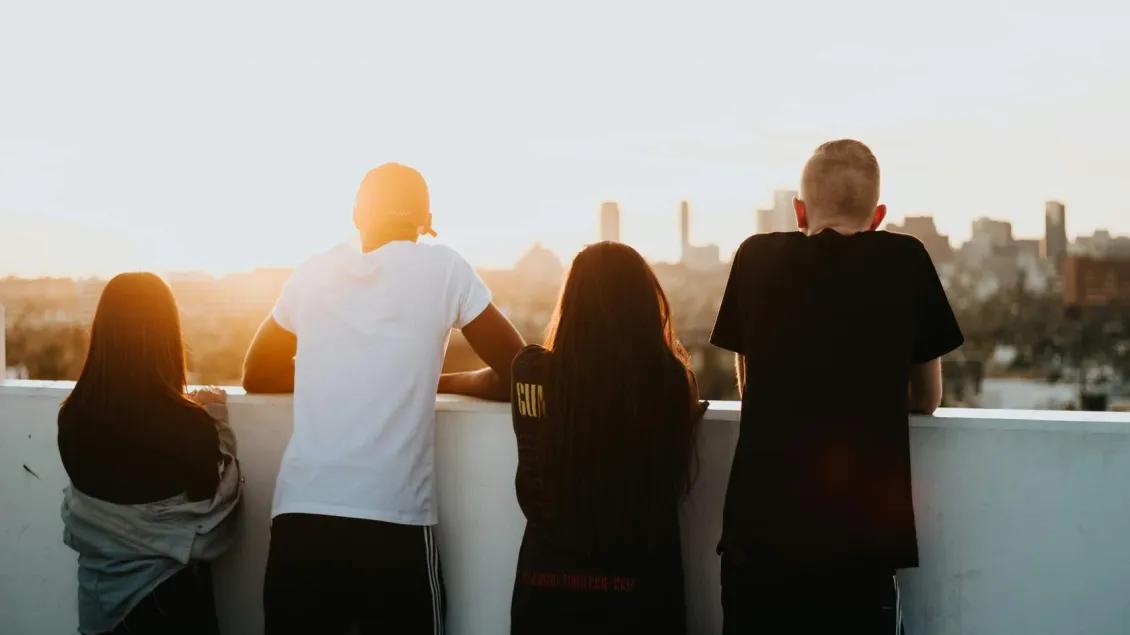 Four teens look out over an urban rooftop