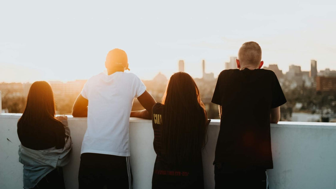 Four teens look out over an urban rooftop