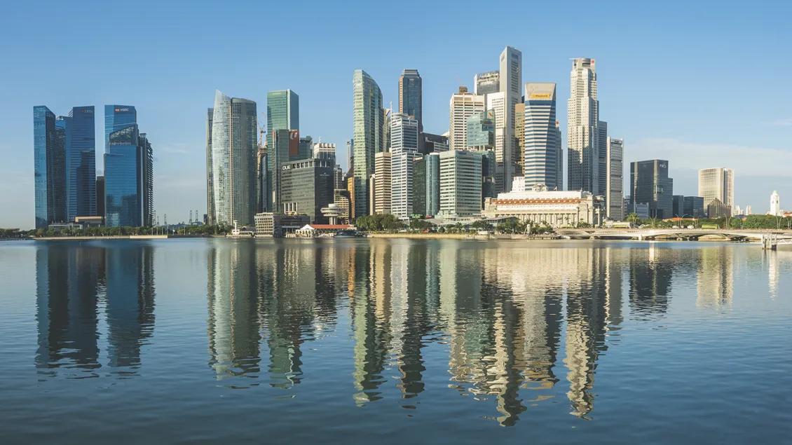An urban area of Singapore with numerous skyscrapers. The Singapore River is in the foreground.