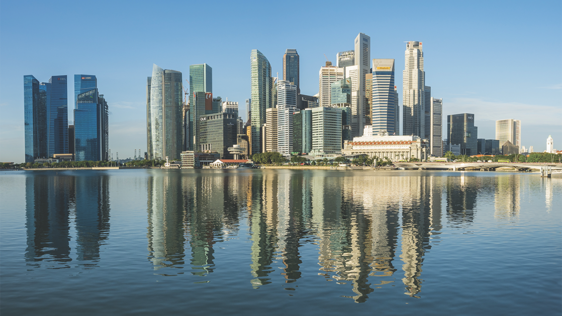 An urban area of Singapore with numerous skyscrapers. The Singapore River is in the foreground.