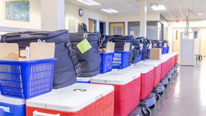 Red coolers with white lids are stacked in a row