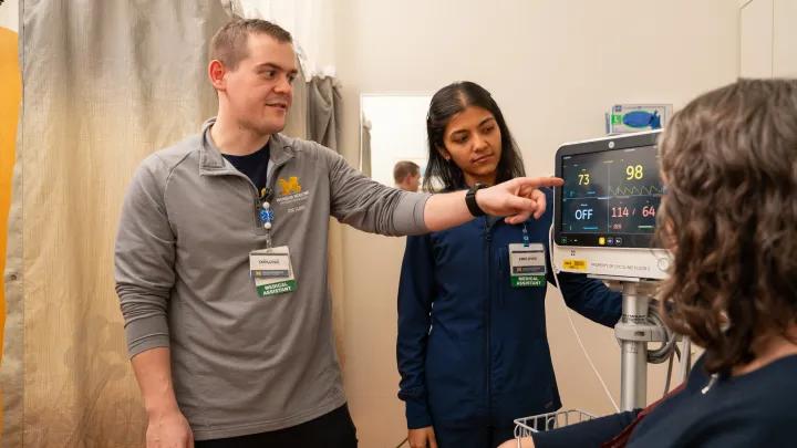 male medical assistant points to a patient's monitor