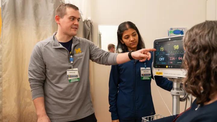 Male medical assistant points to a patient monitor