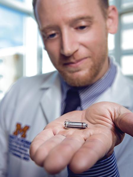 Male doctor holding tiny pacemaker in his hand