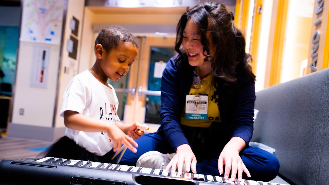 child playing piano happy with music therapist also playing and both smiling happy