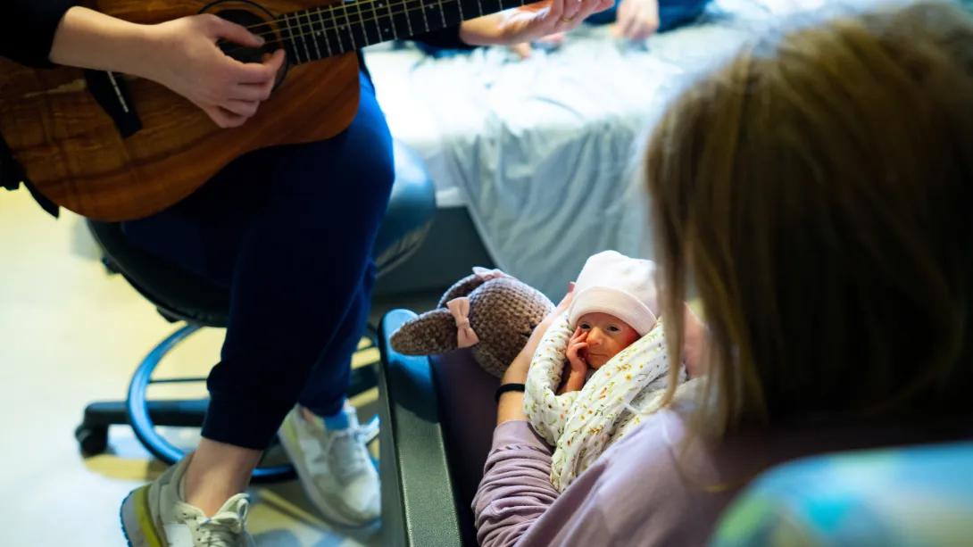 little infant wrapped up with mom looking at camera sweetly