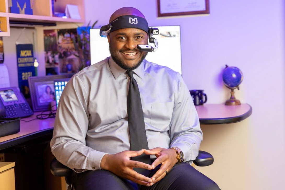 man in shirt and tie smiling at camera in office with headset on