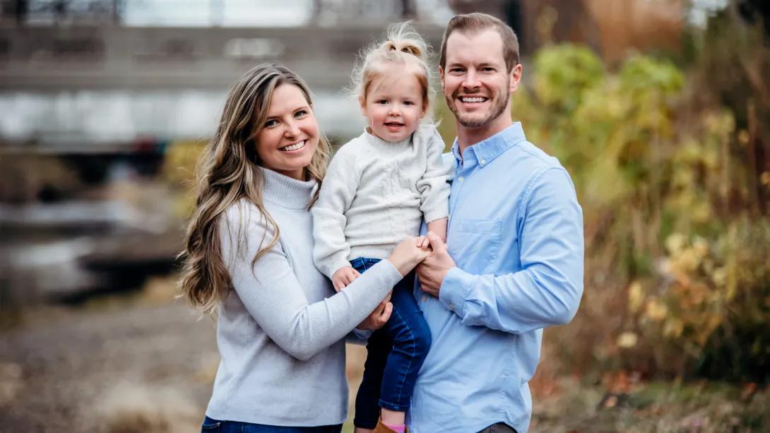 family smiling together holding daughter