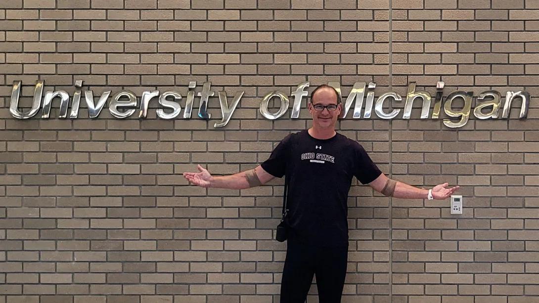 man standing in front of UM sign in hospital smiling 