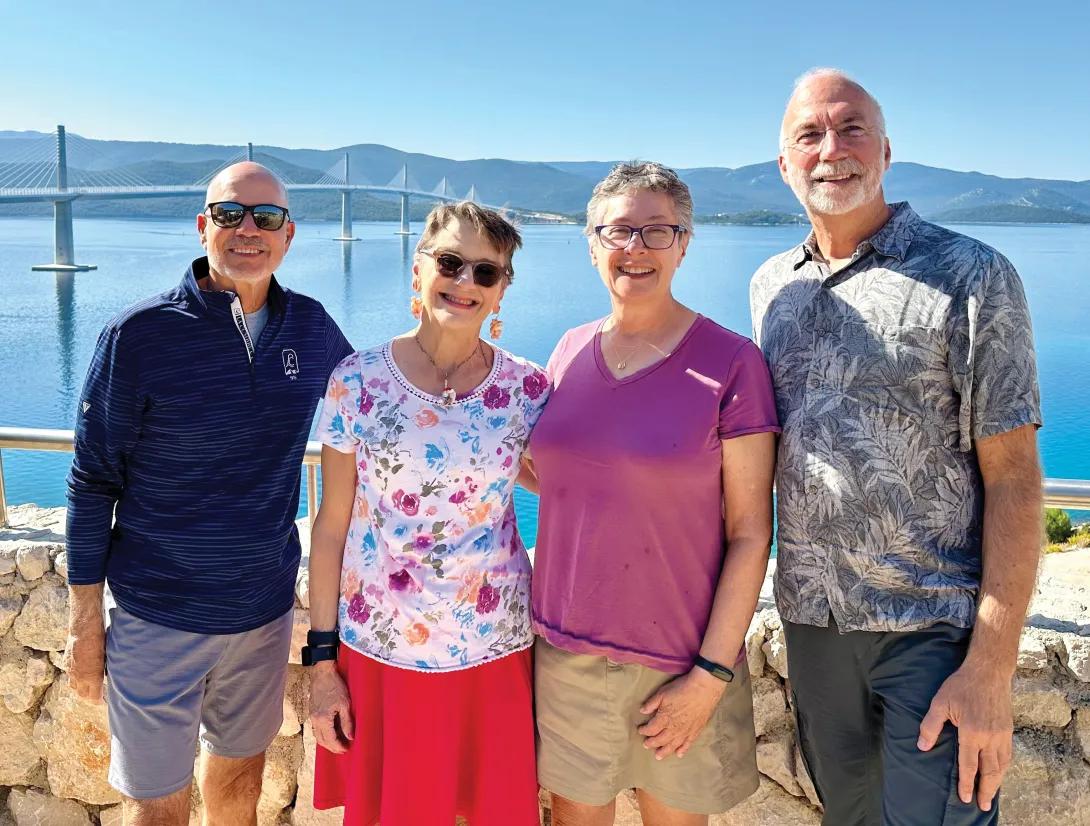 Four people standing in front of the sea. 