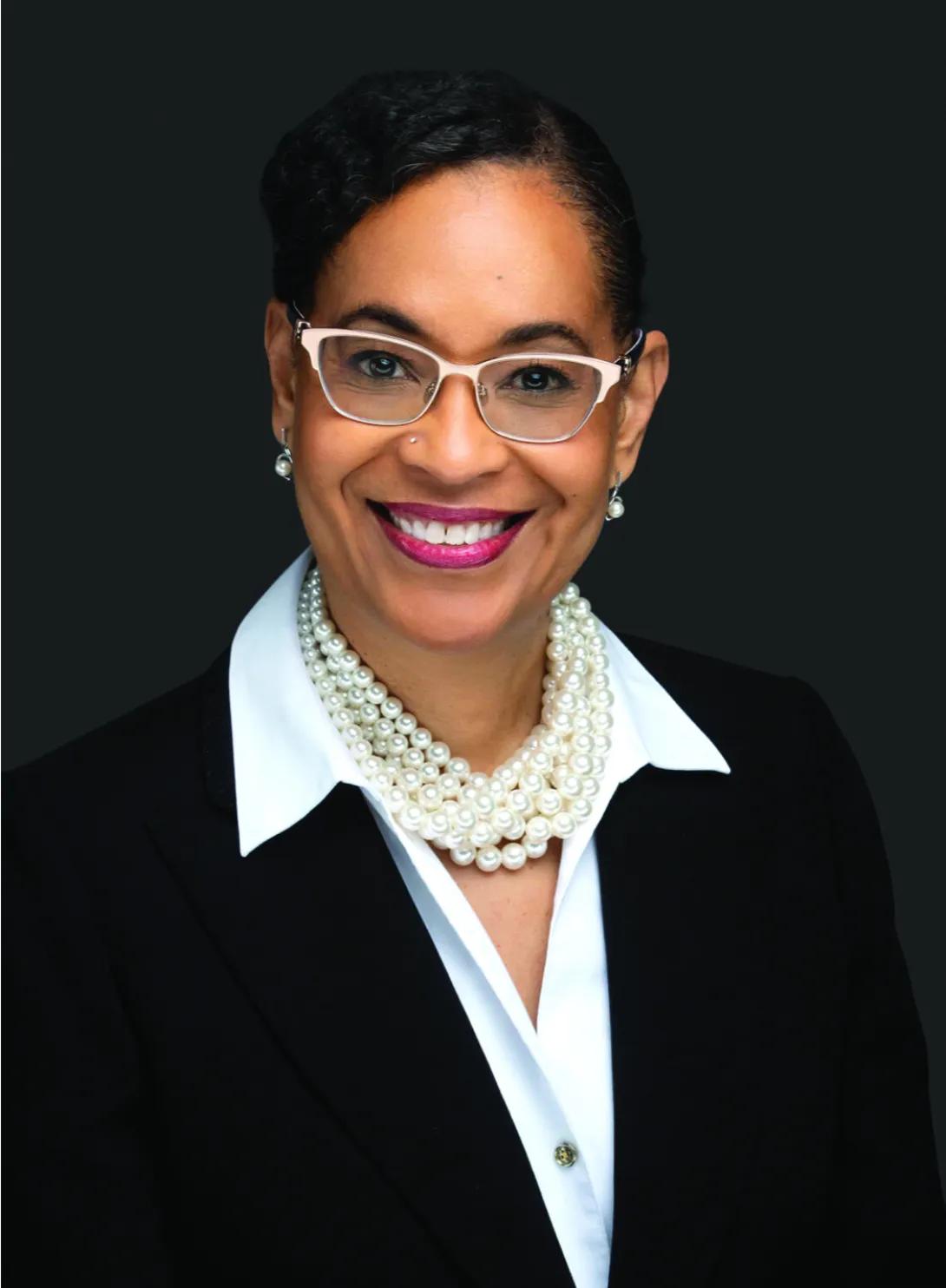 Headshot of Toni. She's wearing a black suit with a white blouse and a pearl necklace.