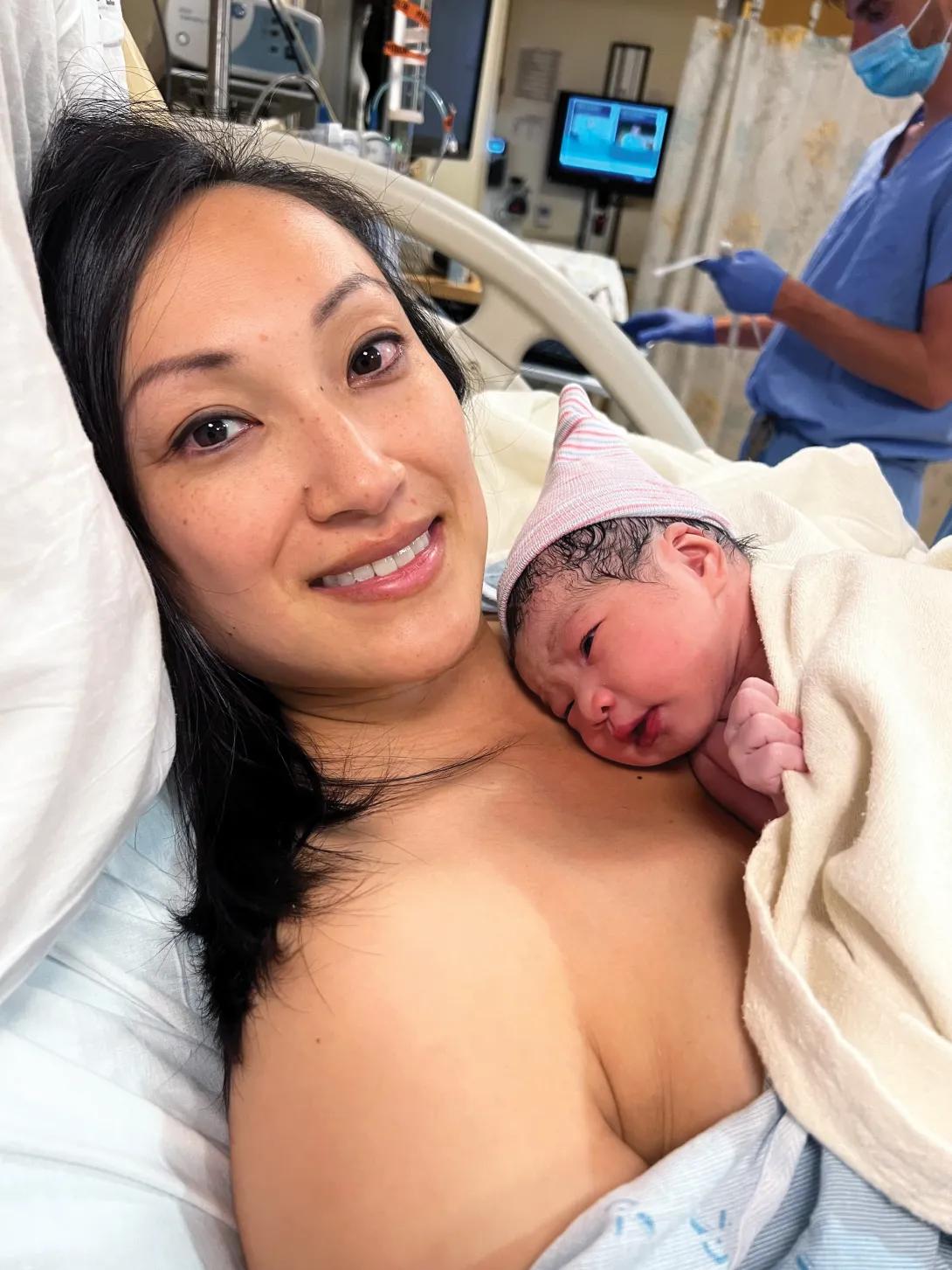Woman lying in a hospital bed with a newborn baby on her chest.