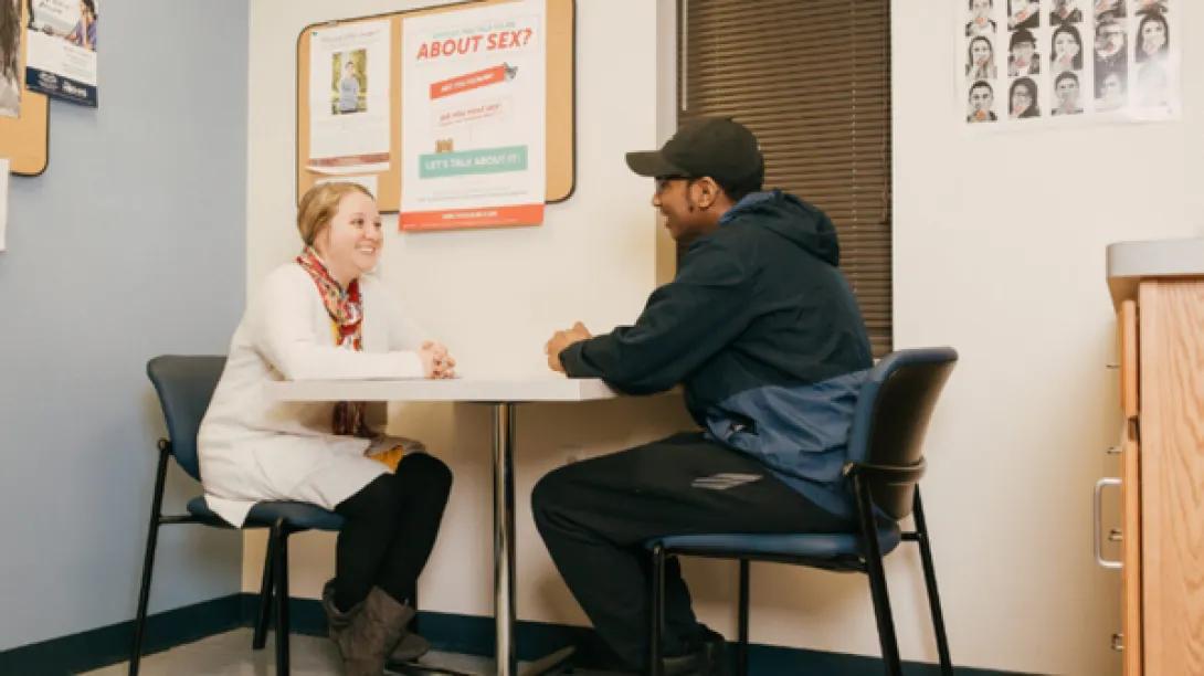 Teen boy speaks with provider at table