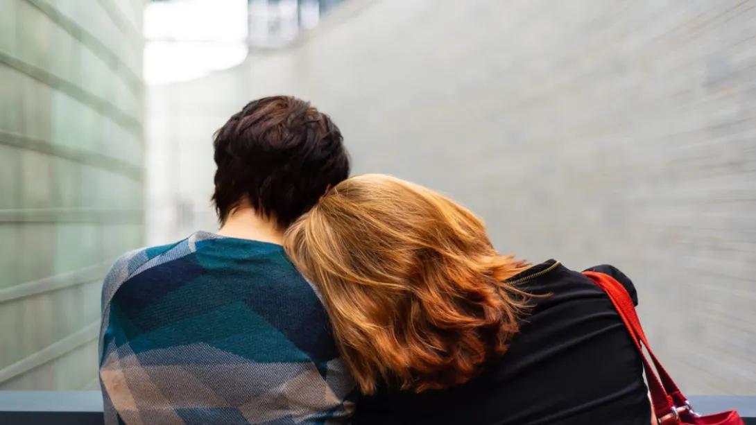 young woman rests head on someone's shoulder