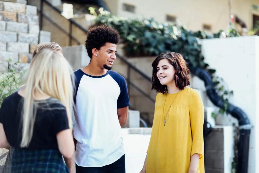 A group of young people smiling and talking to each other.