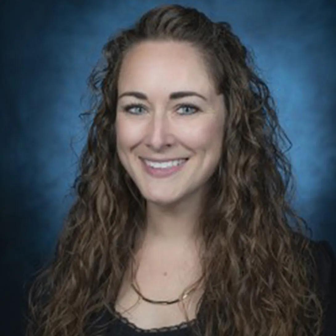 Young white woman with blue eyes and long wavy hair pulled back at the forehead