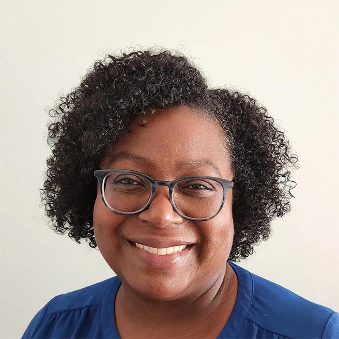 Smiling Black woman wearing glasses and a blue top