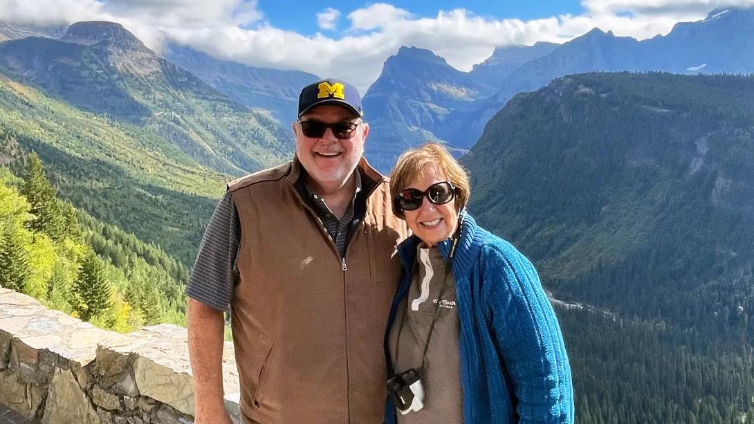 man and woman hiking with mountains and blue sky behind them