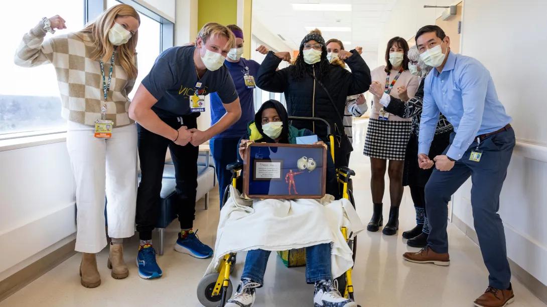 clinical team in hallway with masks on and making strong poses around kid