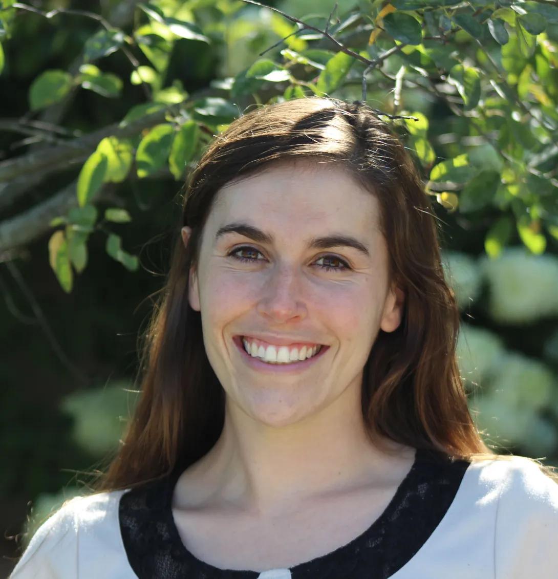 Smiling headshot of Alexa Wutt with summer foliage in the background