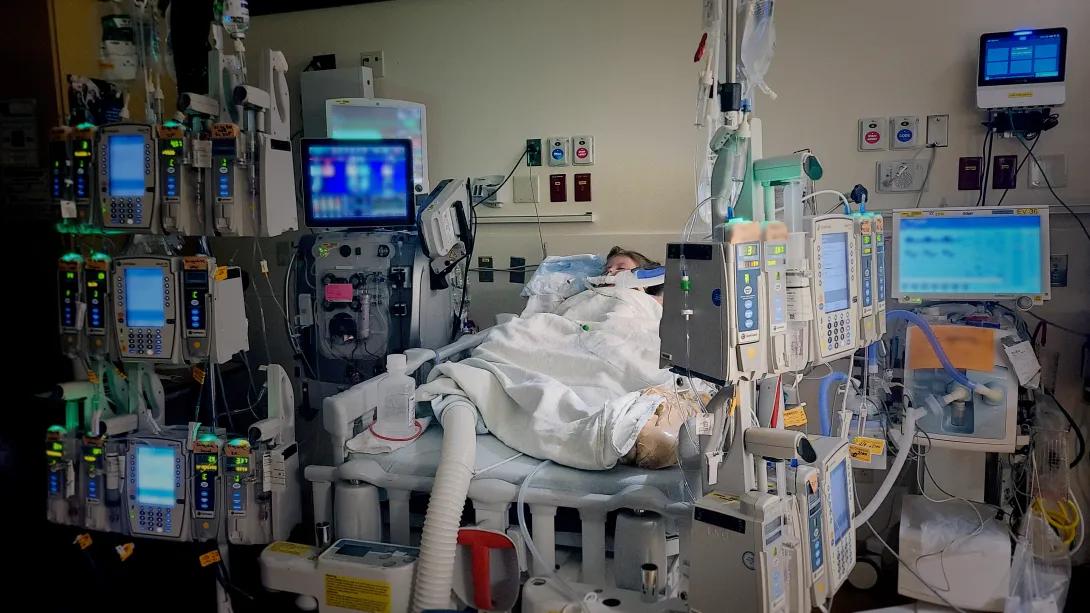 child in hospital bed with machines hooked up all around her