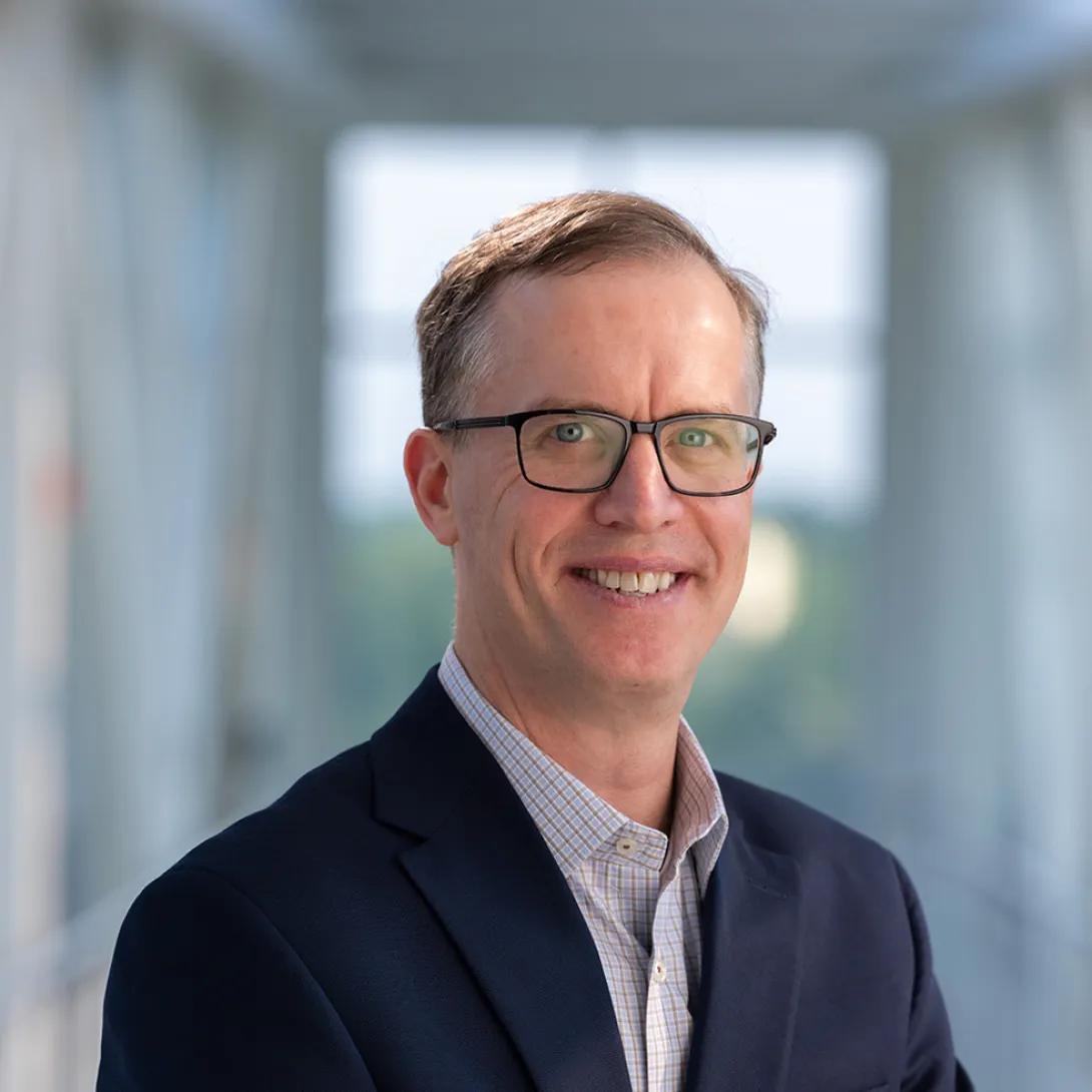 David Miller wearing glasses and blue jacket smiling  