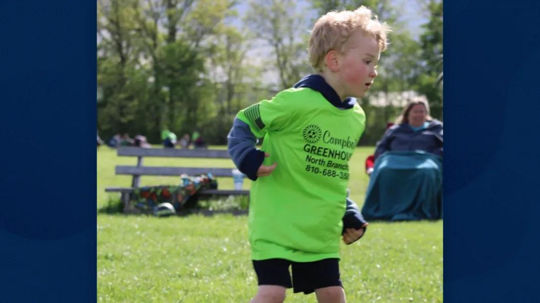 kid running soccer green shirt outside