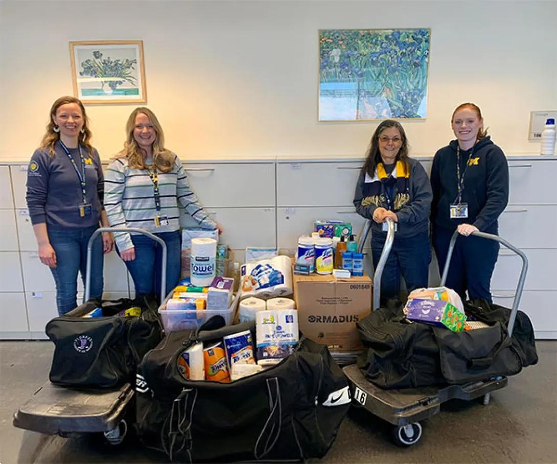 Four women stand together with pantry items.
