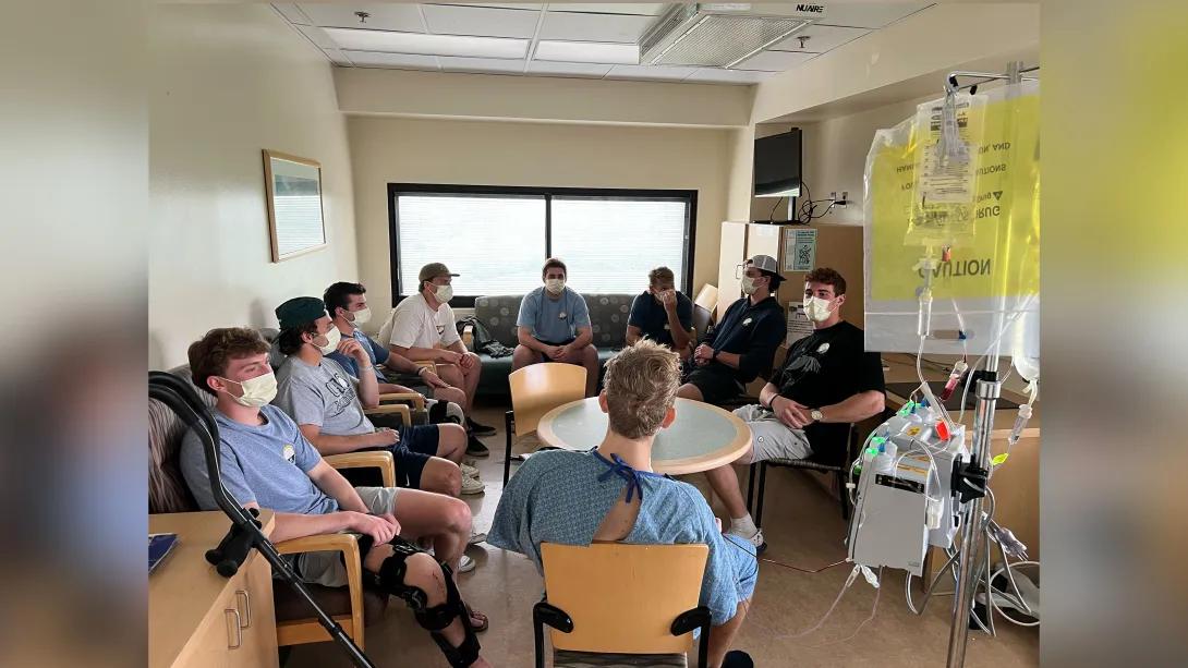 teammates sitting around patient getting card in hospital room