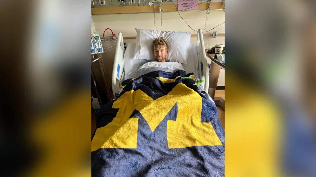 michigan blanket over college student in hospital bed