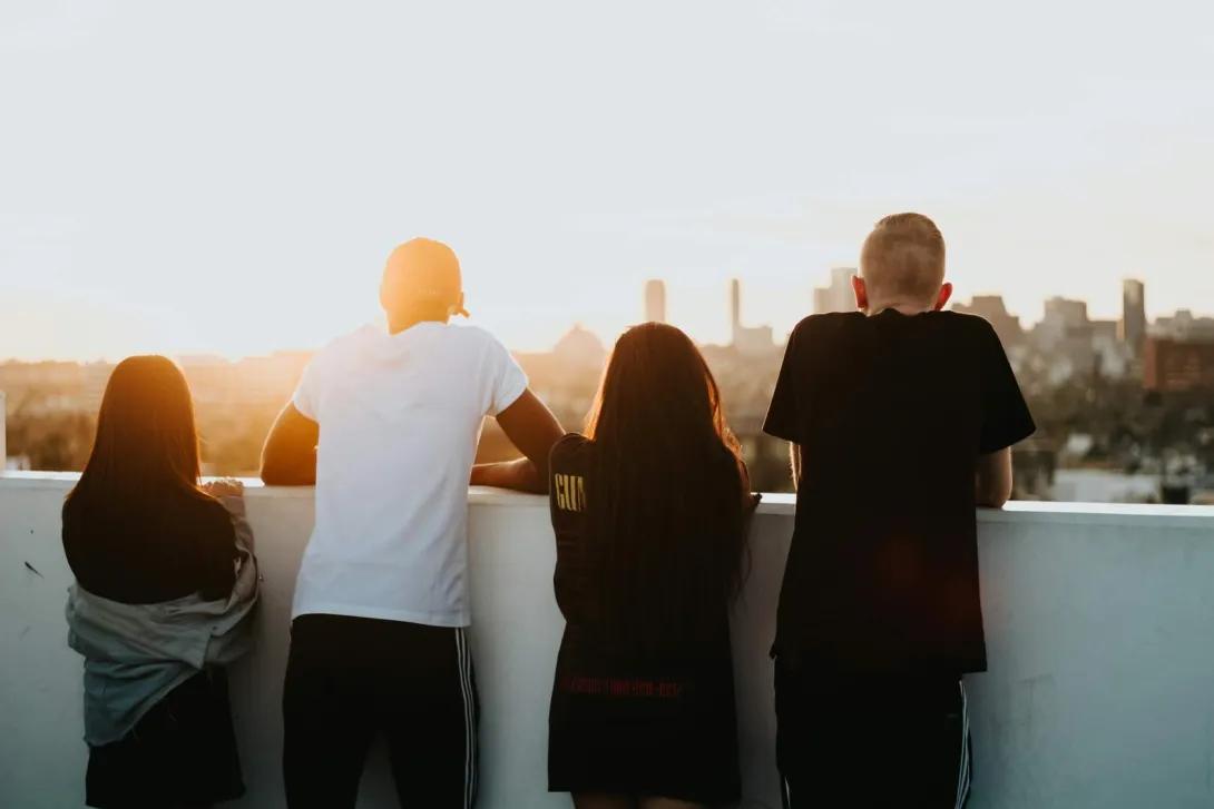 Four teens look out over an urban rooftop