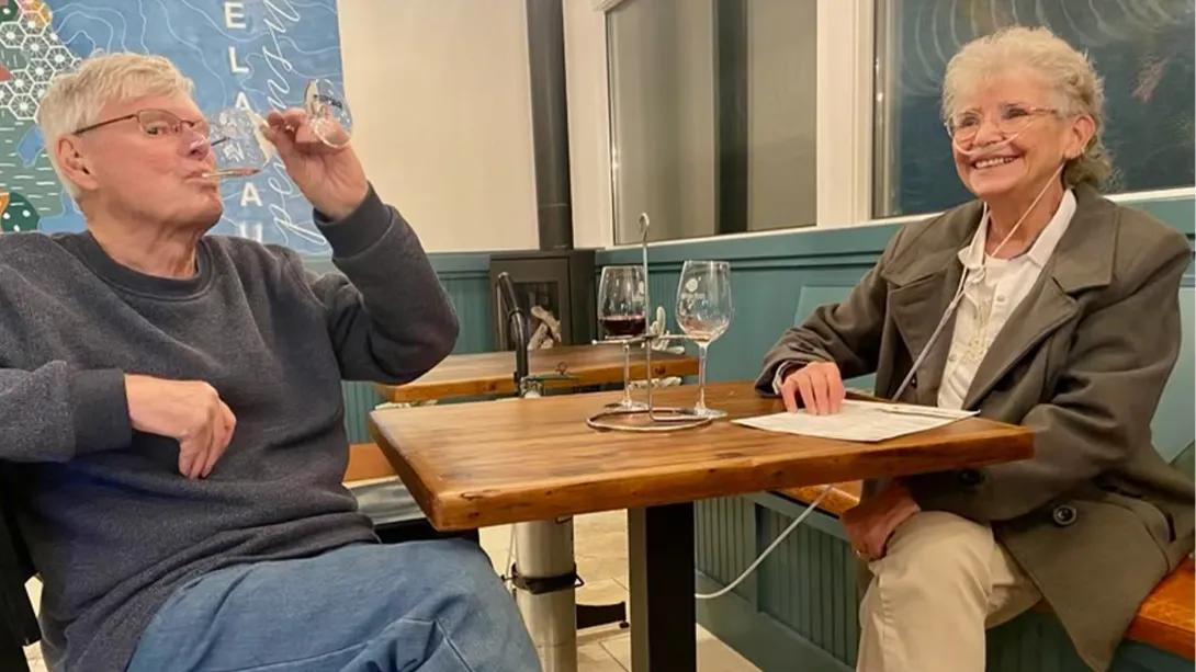 husband and wife at table with wine smiling