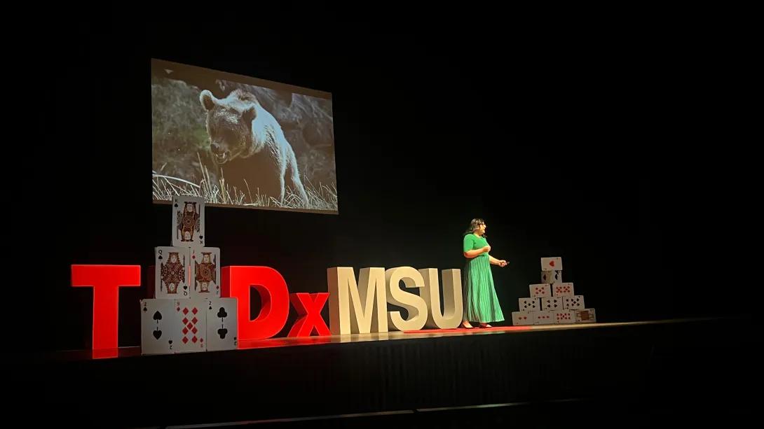 woman on stage green dress ted talk