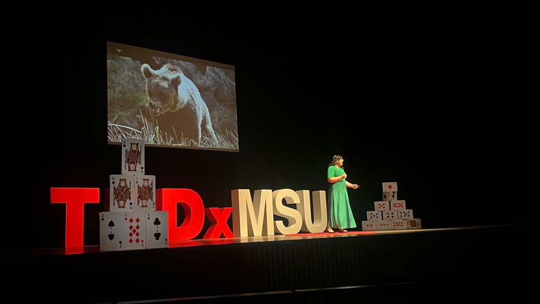 woman on stage green dress ted talk