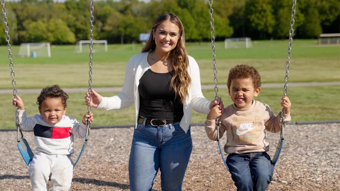 mom inbetween boys on swings background soccer field everyone smiling