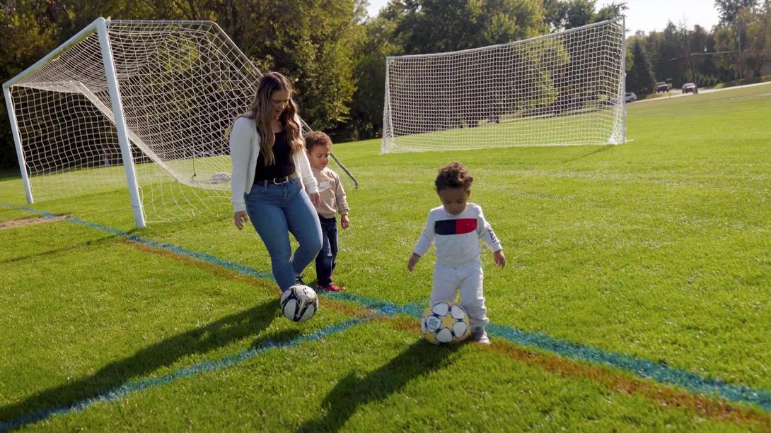 mom with two boys kicking soccer ball