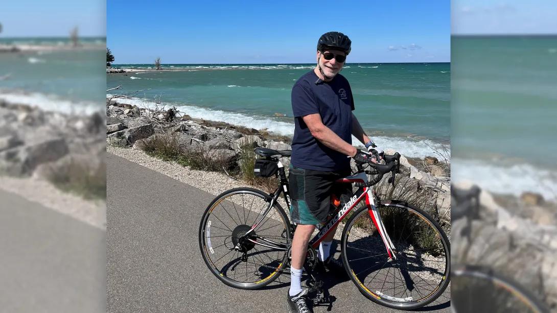 man biking with ocean in background and rocks