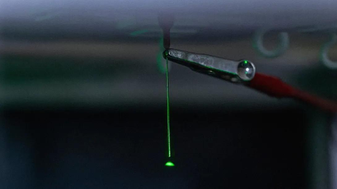 laser with green line dropping down dark background 