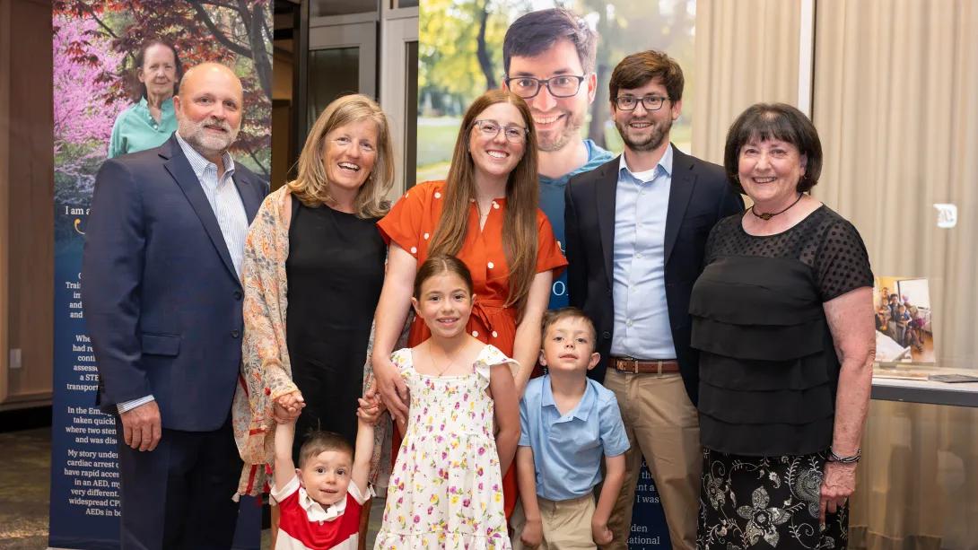 A family poses for a photo at an event in front of a poster with a woman on it